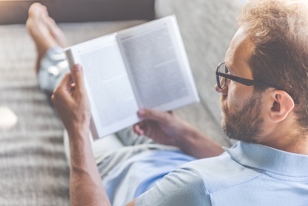 Geschäftsmann in der Kleidung und in den Brillen ein Buch lesend