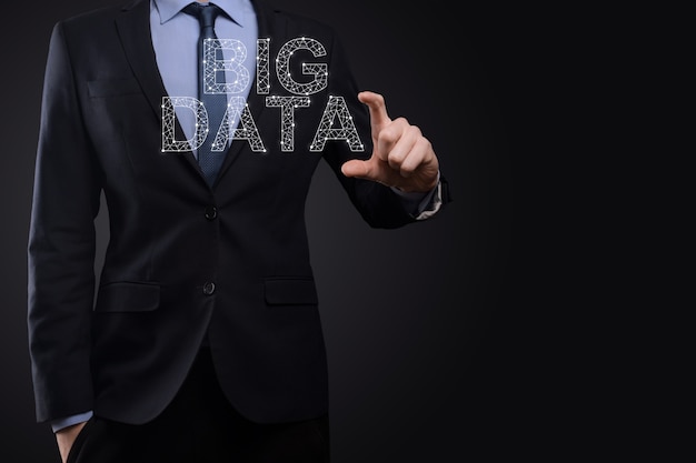 Geschäftsmann in einem Anzug auf dunklem Hintergrund hält die Aufschrift BIG DATA. Storage Network Online Server Concept.Social Network oder Business Analytics Darstellung.