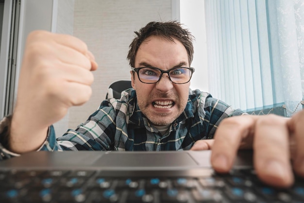 Geschäftsmann in einem hemd im büro schlägt auf die tastatur wütender mann, der gegen die informationstechnologie flucht und flucht, und sein computer sorgt sich und ärgert das konzept, computer zu hassen