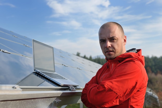 Geschäftsmann-Ingenieur mit Laptop bei Sonnenkollektoren pflanzen Öko-Energiefeld im Hintergrund