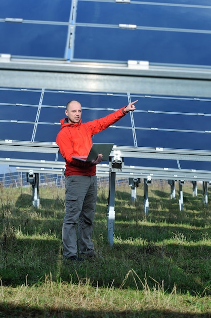 Geschäftsmann-Ingenieur mit Laptop bei Sonnenkollektoren pflanzen Öko-Energiefeld im Hintergrund