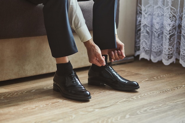 Geschäftsmann kleidet Schuhe Mann, der sich morgens vor der Hochzeitszeremonie für den Bräutigam fertig macht