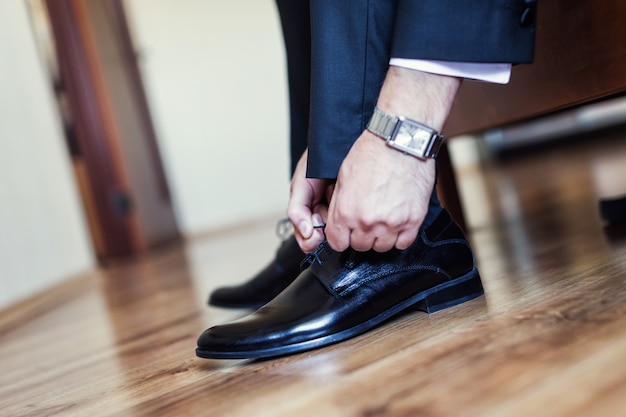 Foto geschäftsmann kleidet schuhe, mann macht sich bereit für die arbeit, bräutigam morgen vor der hochzeitszeremonie