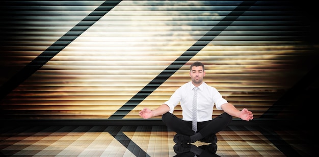 Geschäftsmann meditiert in Lotus-Pose gegen Raum mit großem Fenster mit Blick auf die Landschaft