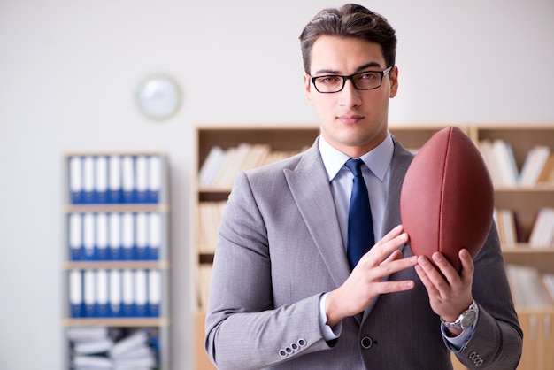 Geschäftsmann mit amerikanischem Fußball im Büro