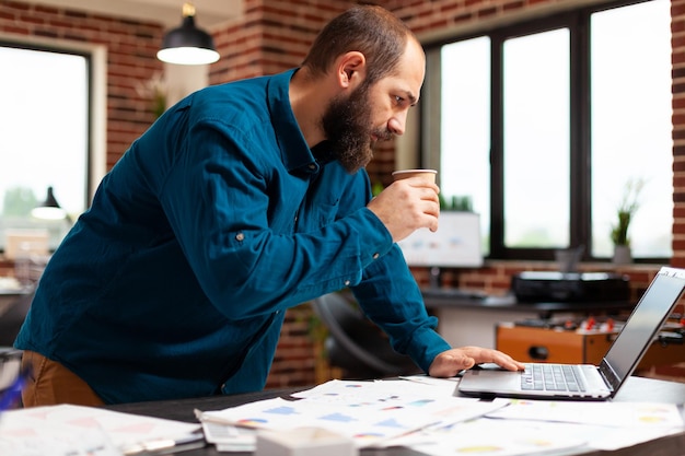 Geschäftsmann mit Blick auf den Computerbildschirm zur Analyse der Marketingstrategie Planung von Unternehmensinvestitionen bei der Firmenpräsentation im Startup-Büro. Buchhalter analysiert Finanzdiagramme