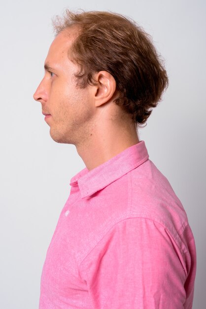 Foto geschäftsmann mit blondem haar, das rosa hemd gegen leerraum trägt