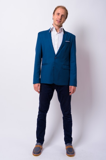 Geschäftsmann mit blondem Haar, der blauen Anzug gegen weiße Wand trägt
