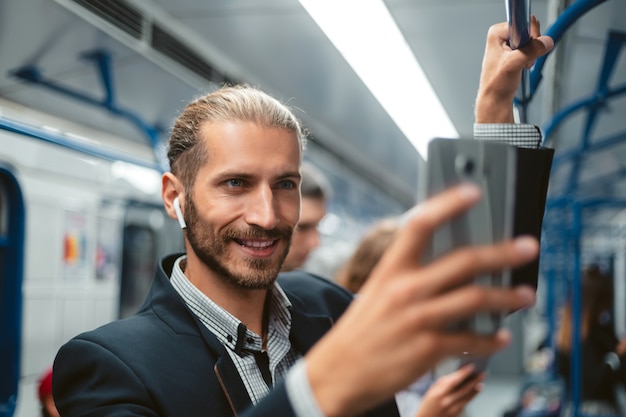 Geschäftsmann mit einem Smartphone, das in einem U-Bahnzug steht