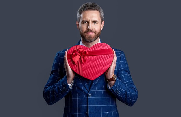 Geschäftsmann mit Geschenk zum Valentinstag isoliert auf rot Geschäftsmann halten Valentinstag vorhanden