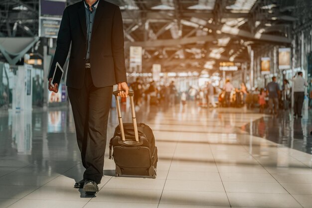 Geschäftsmann mit Handgepäck zu Fuß im Flughafenterminal. Geschäftsmann mit Koffer beim Gehen durch ein Passagierabfertigungsterminal im Flughafen. Geschäftsmann Reisende Reise Geschäftsreise.