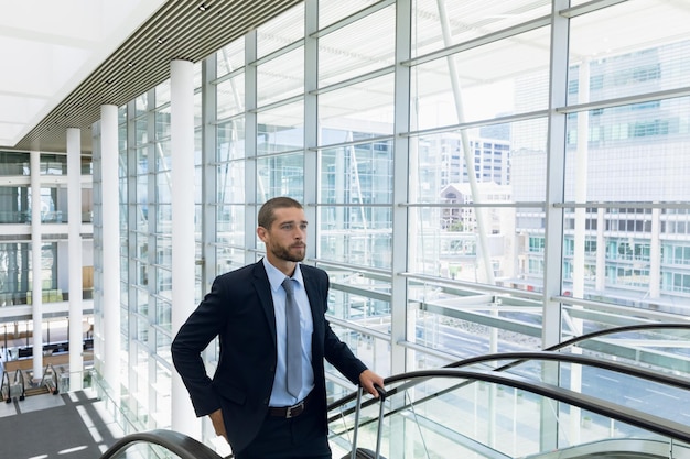 Geschäftsmann mit Koffer auf einer Rolltreppe