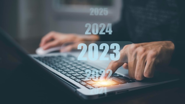 Geschäftsmann mit Laptop mit neuer Planung Geschäftsmann mit Stiftberührung auf 2023 Jahreszahl Beginn des neuen Jahreskonzepts Digitale Trends Industrie- und Geschäftstrendstrategieinvestitionen