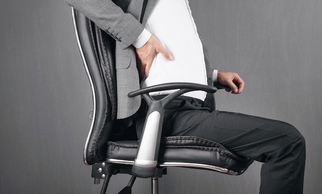 Geschäftsmann mit Rückenschmerzen im Bürostuhl sitzen.