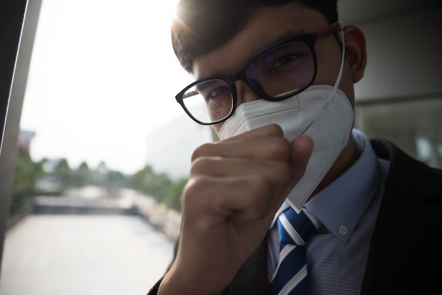 Geschäftsmann mit schützender Gesichtsmaske und Husten, Coronavirus und PM 2.5 kämpfen