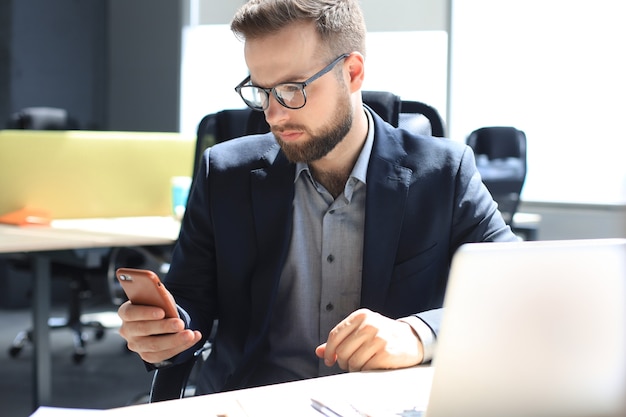 Geschäftsmann mit seinem Handy im Büro.