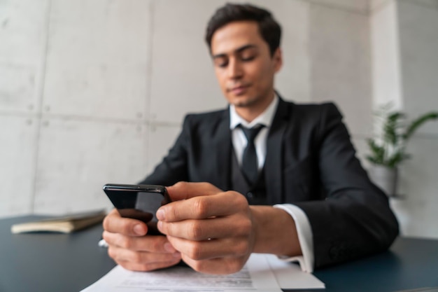 Geschäftsmann mit Smartphone am Bürotisch