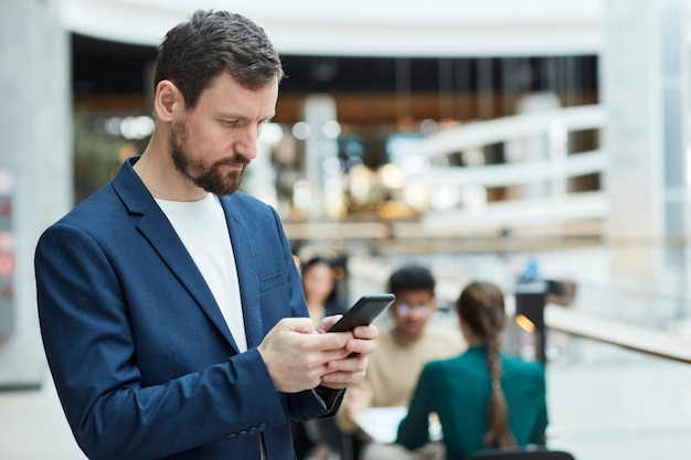 Geschäftsmann mit Smartphone im Einkaufszentrum