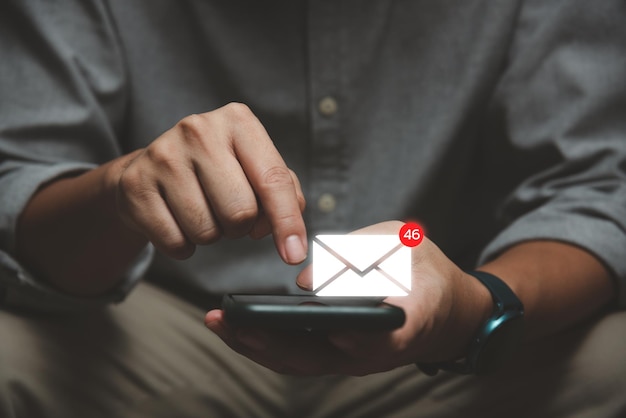 Geschäftsmann mit Smartphone mit Popup-Icon-E-Mail und Benachrichtigung für geschäftliche E-Mail und Kommunikationstechnologie