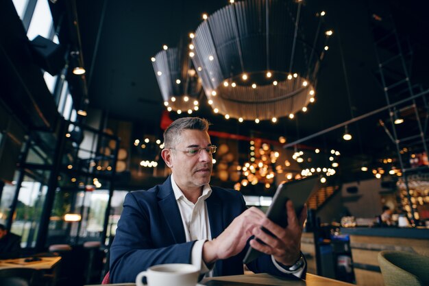 Geschäftsmann mit Tablette im Café.