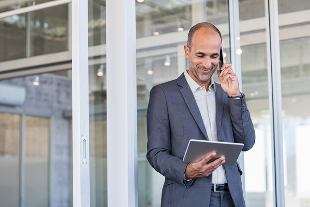 Geschäftsmann mit Tablette und Telefon