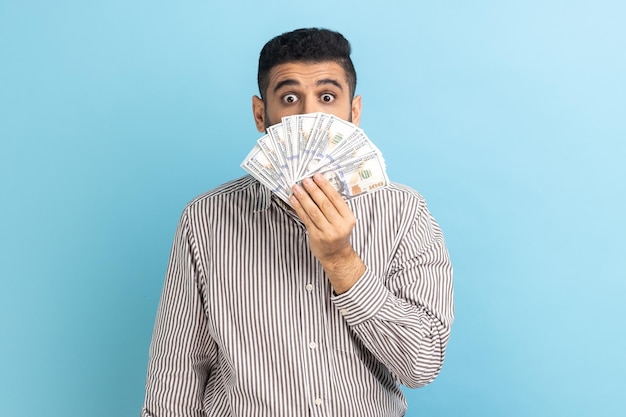 Geschäftsmann mit überraschten großen Augen, die das halbe Gesicht mit großem Gewinn der Dollarbanknoten bedecken