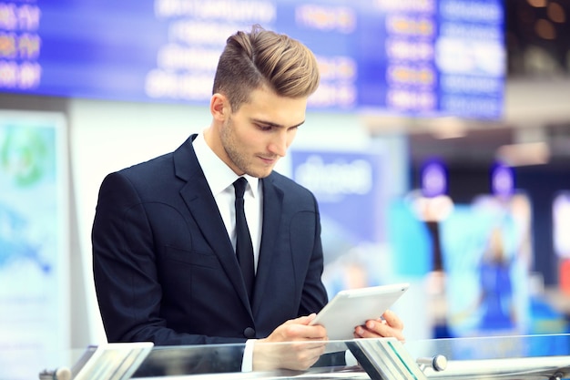 Geschäftsmann nutzt digitales Tablet in der Abflughalle des Flughafens