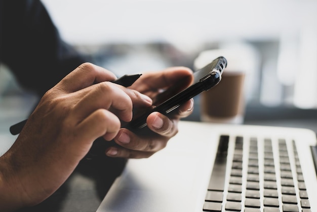 Geschäftsmann nutzt morgens eine WLAN-Verbindung für Mobiltelefone auf dem Schreibtisch mit einer Tasse Kaffee