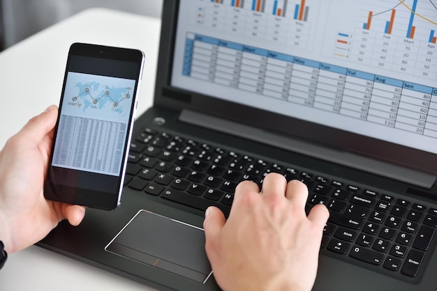 Geschäftsmann nutzt Smartphone mit Grafiken und Diagrammen