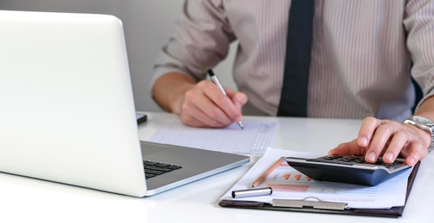 Geschäftsmann oder Buchhalter mit Taschenrechner und Laptop-Computer im Büro Geschäftsmann, der zu Hause Finanzmarketing und Buchhaltungskonzept arbeitet