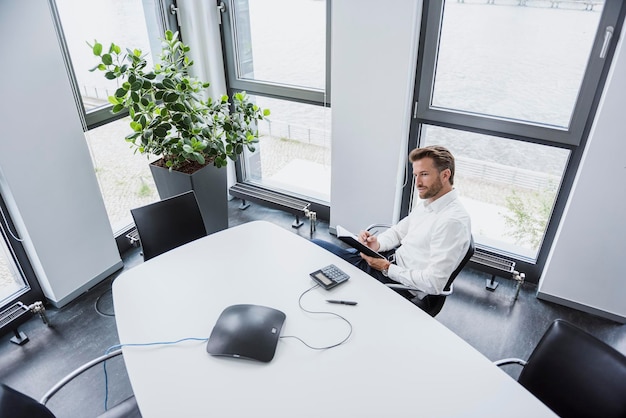 Geschäftsmann sitzt am Besprechungstisch in seinem Büro