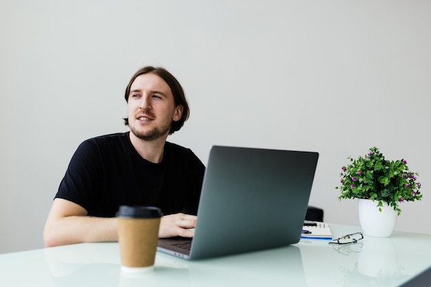 Geschäftsmann sitzt am Schreibtisch und arbeitet an Laptop-Computer