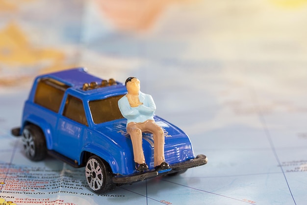 Geschäftsmann sitzt auf blauem Auto für Reisen um die Welt