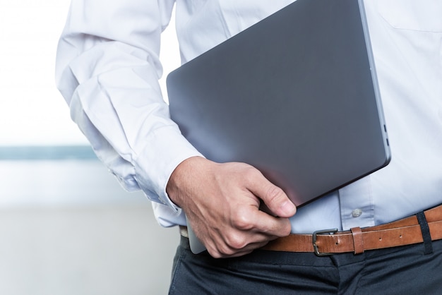 Geschäftsmann stehend beim Tragen eines Laptops