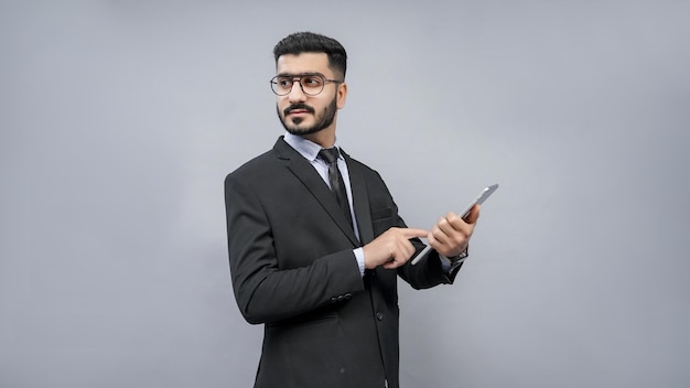 Geschäftsmann stehend mit Brille posiert grauen Hintergrund im schwarzen Anzug indisches pakistanisches Modell