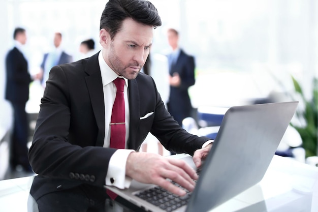 Geschäftsmann tippt auf einem Laptop, der an seinem Schreibtisch sitzt