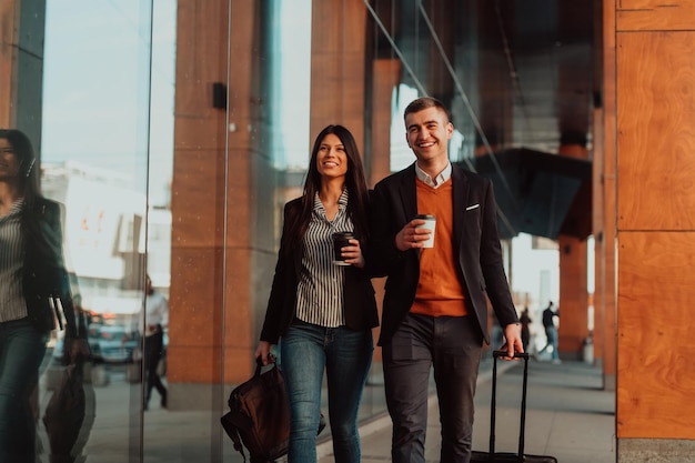 Geschäftsmann und Geschäftsfrau sprechen und halten Gepäck auf einer Geschäftsreise und tragen frischen Kaffee in ihren Händen. Unternehmenskonzept. Hochwertiges Foto