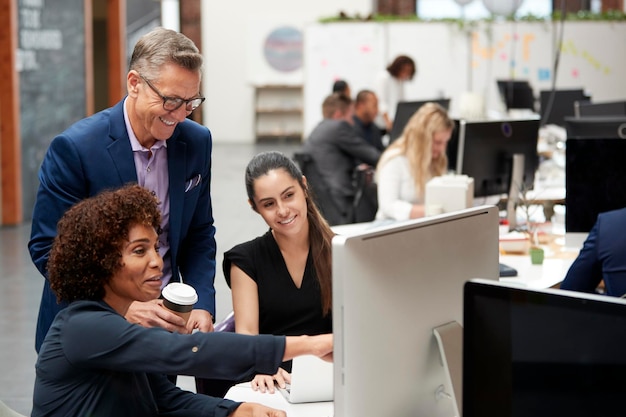 Geschäftsmann und Geschäftsfrauen, die am Computer auf dem Schreibtisch im Großraumbüro arbeiten