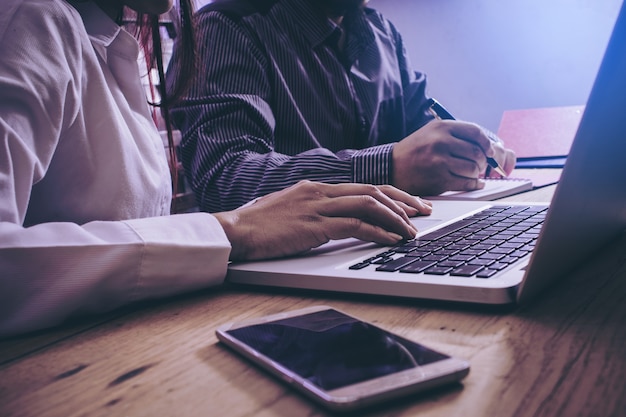 Geschäftsmann und Partner, die berichteten Gewinne auf Laptop überprüfen.