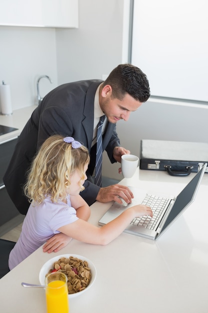 Geschäftsmann und Tochter, die bei Tisch Laptop verwenden