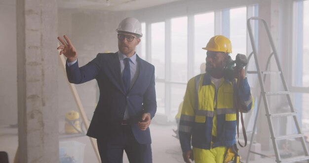 Foto geschäftsmann und vorarbeiter im bauarbeiterhelm diskutieren renovierungsplan auf der baustelle