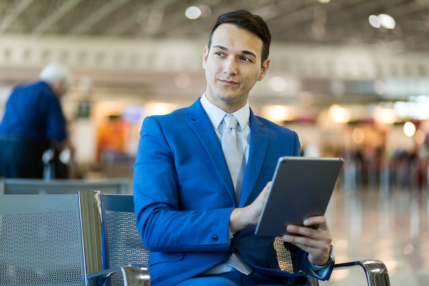 Geschäftsmann unter Verwendung der elektronischen Tablette in einem Flughafen