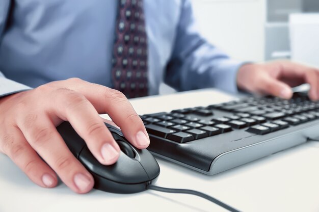 Geschäftsmann unter Verwendung des Computers mit den Händen, die auf einer Tastatur schreiben