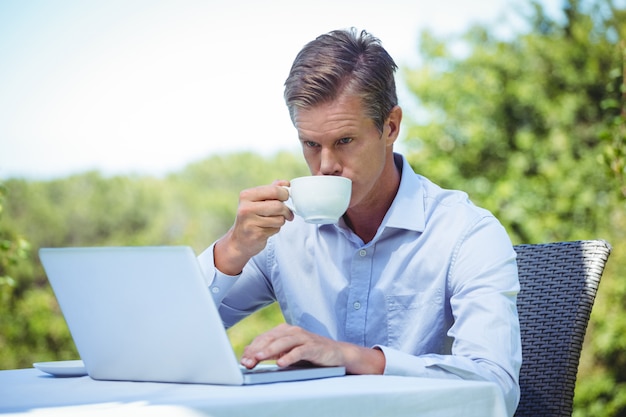 Geschäftsmann unter Verwendung des Laptops mit Kaffee