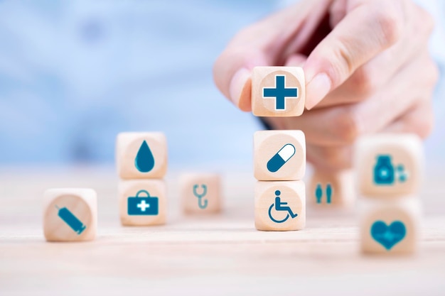 Geschäftsmann wählt ein Emoticon-Ikonen Gesundheitsmedizinisches Symbol auf Holzblock Gesundheitsmedizinische