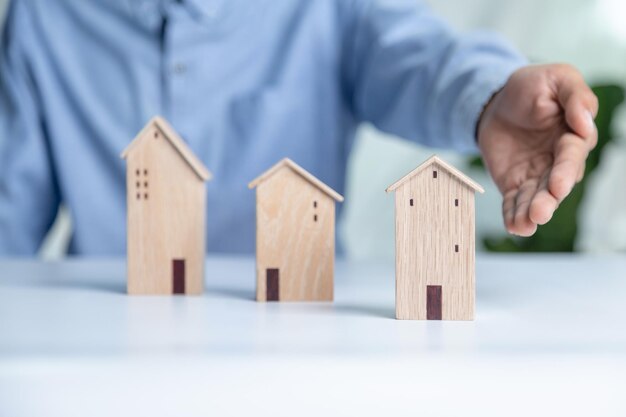 Geschäftsmann wählt Mini-Holzhausmodell aus Modell auf Holztisch Planung zum Kauf eines Immobilienkonzepts von Wählen Sie das Beste