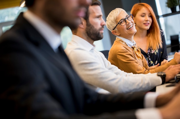 Geschäftsmannexekutive in der Gruppensitzung mit anderen Geschäftsmännern und Geschäftsfrauen im modernen Büro mit Computer