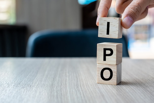 Geschäftsmannhand, die IPO-Wort (Initial Public Offering) mit Holzwürfelblock hält