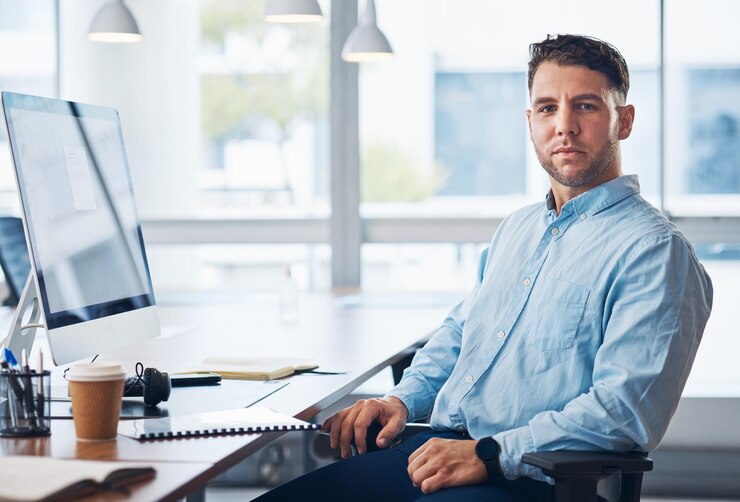 Geschäftsmannporträt und seriöser Finanzberater am Computer mit Dokumenten im Vertrieb am Schreibtisch sitzend. Männlicher Unternehmensangestellter am Desktop-PC auf Stuhl, bereit für Finanzberatung, Darlehen oder Hilfe