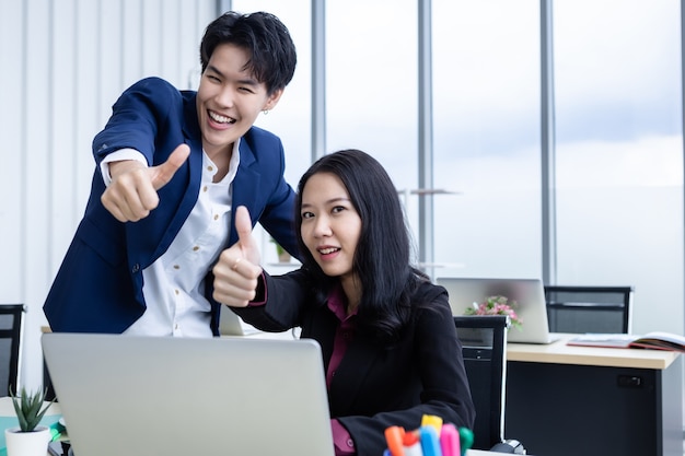 Geschäftspartner tomboy Lesben und Geschäftsfrauen, die Daumen hocharbeiten und zuversichtlich einen erfolgreichen Geschäftsplan auf dem Laptop zeigen. Zusammenarbeit mit einem Lächeln im Gesicht im Büro